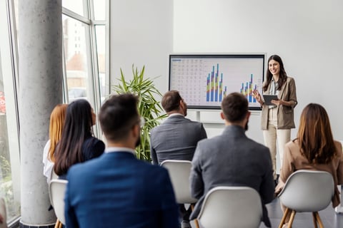 Female presenter showing financial charts and data on interactive screen during webinar